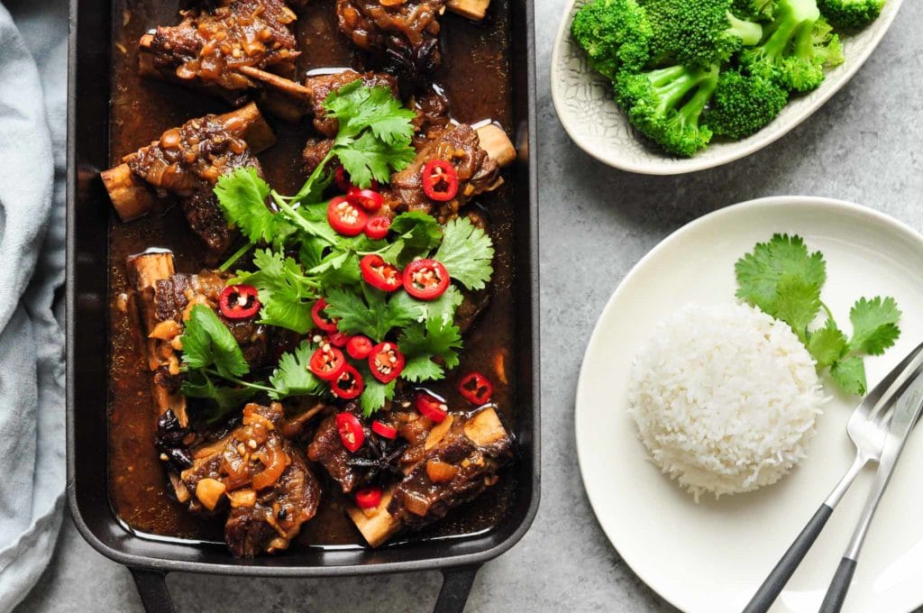 beef short ribs with cilantro and sliced chillies in black roasting tray